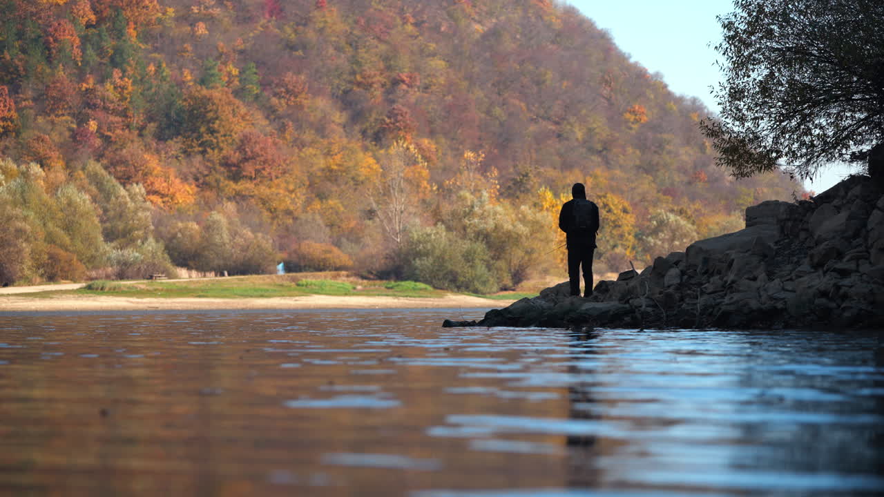 A fisherman enjoys the autumn scenery by the lake