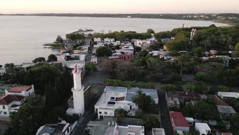 drone rotate around lighthouse in colonia del sacramento uruguay town during warm golden hours sunset