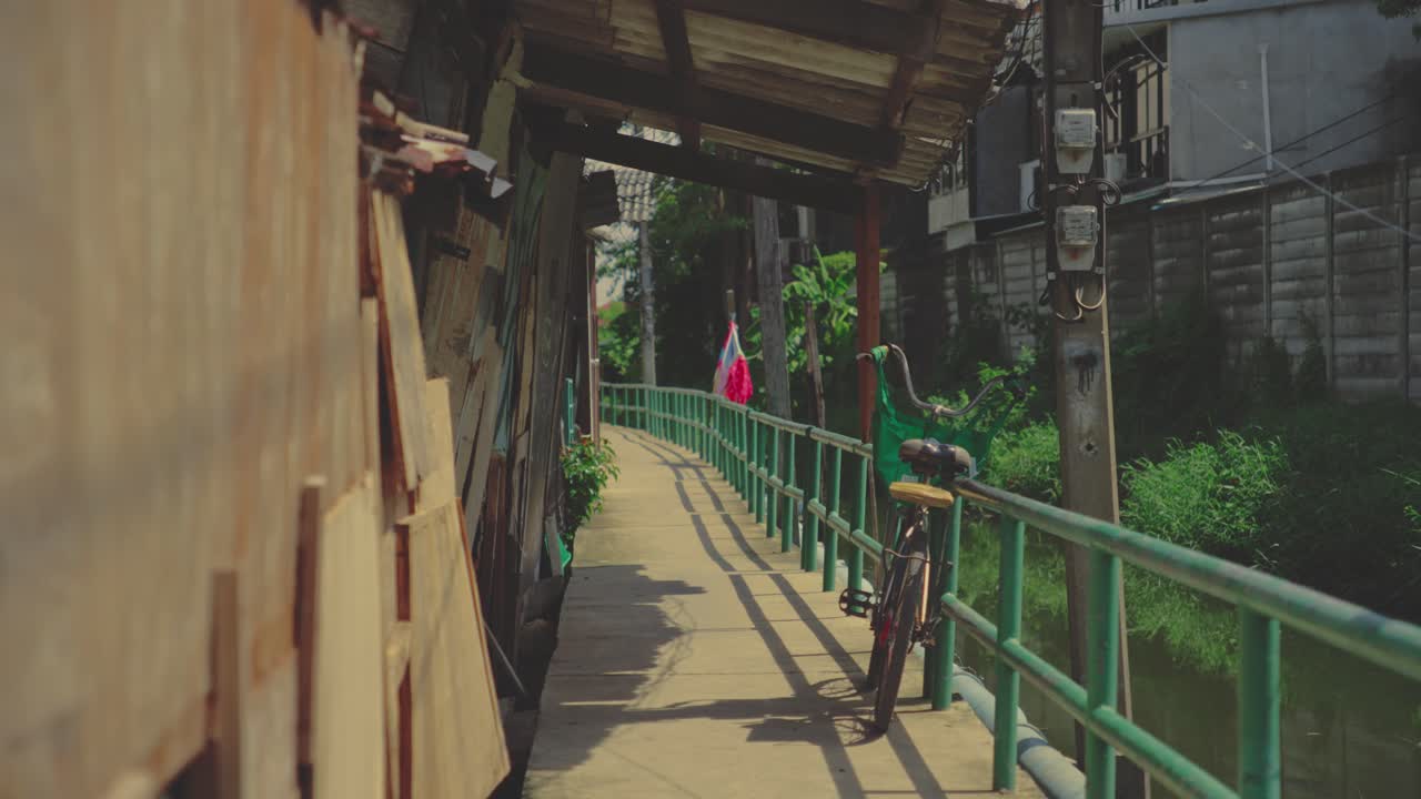 A Narrow Walkway by a Canal With a Parked Bicycle and a Thai Flag in the Background in Bangkok, Thailand - Close Up