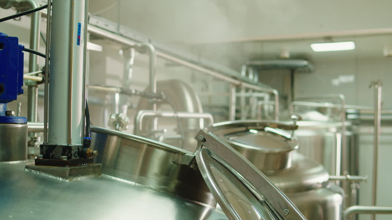 Craft beer production factory, brewery manufacture. Putting barley malt grains in conveyor close-up. Brewing, cooking alcohol in metal vats bottles