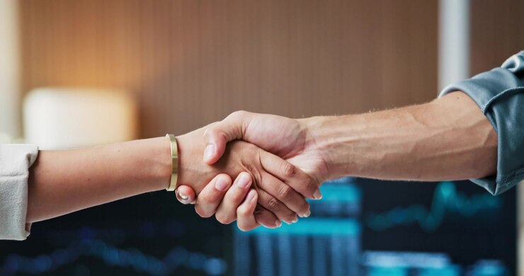 Business Professionals Shaking Hands in Front of Financial Data Screens