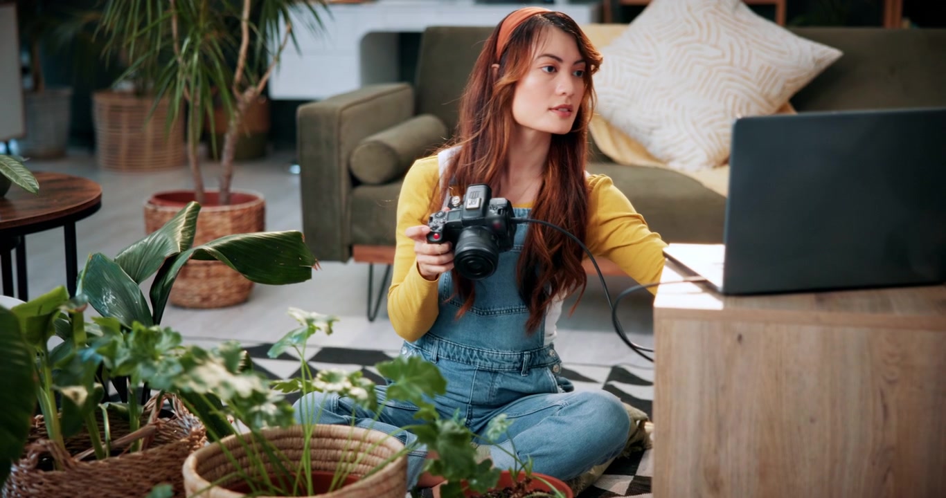 Giovane fotografa che rivede le foto sulla fotocamera collegata al laptop