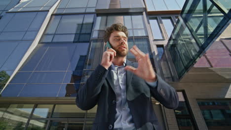 stressed businessman calling cellphone at business center exterior. annoyed boss