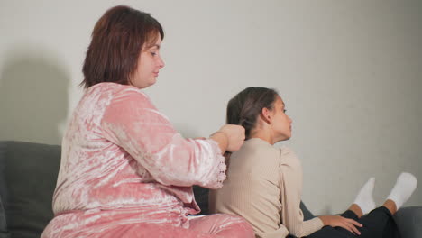 Nanny braiding girl&#039;s hair, intimate caregiving moment, close-up shot, calm atmosphere, child relaxed, sitting on sofa, gentle grooming, home setting, family bonding, personal touch
