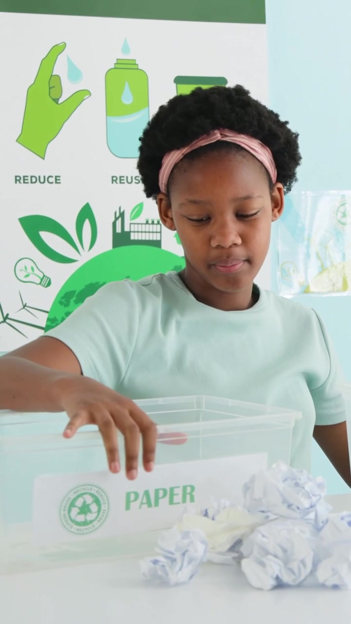 Vertical video: Pointing at posters at school, youth pink headband teaching sorting into PAPER bin