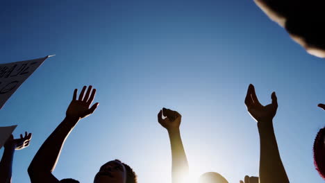 silhouettes of people with raised arms against a bright sky