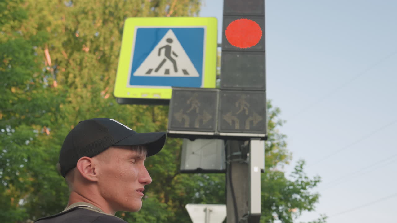 Commuter Facing Pedestrian Crossing And Countdown, Over Shoulder View With Cap, LED Number Visible, Green Circle Illumination, Trees And Sky Backdrop, Urban Afternoon, Tentative Step Forward As Light