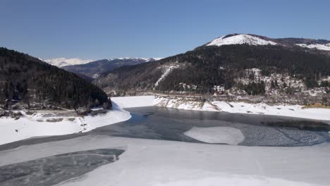 drone footage of a frozen lake with surrounding mountains in macedonia