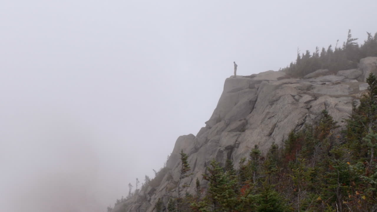 한 등산객이 뉴욕의 아디론댁 산에서 불길한 안개가 자욱한 날씨에 절벽 가장자리까지 걸어가 서 있습니다.