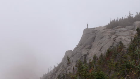 Un-Excursionista-Camina-Y-Se-Para-Al-Borde-De-Un-Acantilado-En-Un-Clima-Neblinoso-Ominoso-En-Las-Montañas-Adirondack-De-Nueva-York