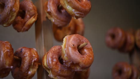 toma panorámica lenta de docenas de donas glaseadas que cuelgan en varios bastidores de donas