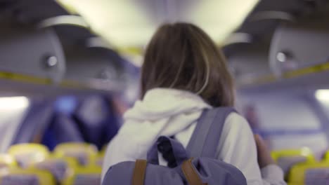 hermosa chica con máscara y mochila en el avión pasando por el corredor