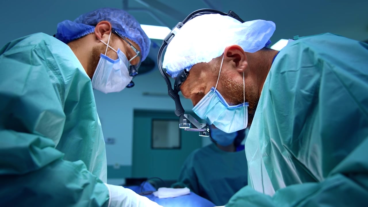 Chirurghi professionisti uomini collaborano durante l'intervento. Medici attenti eseguono un intervento maxillo-facciale.