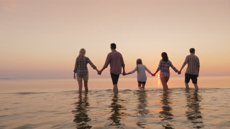 Eltern-Mit-Kindern-Haben-Spaß-Im-Wasser-Schöner-Sonnenuntergang-über-Dem-Meer