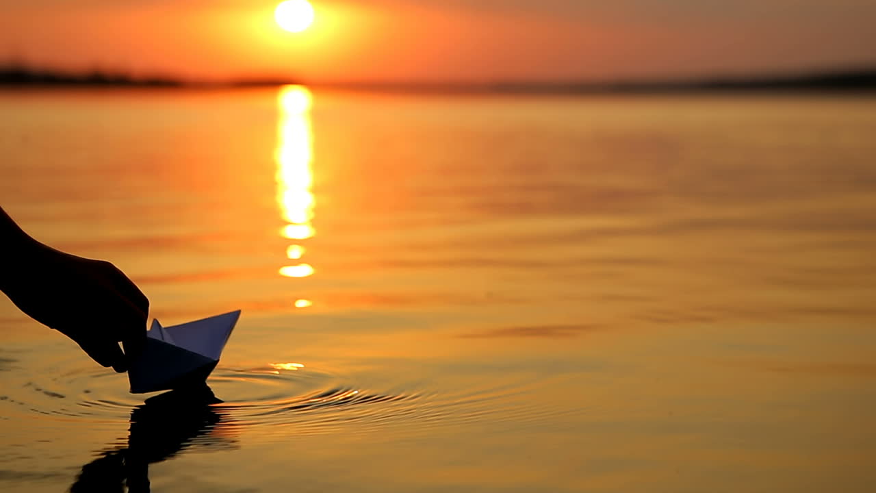 Boy With Paper Boat Near Water. Boy standing and holding paper boat on beach near water