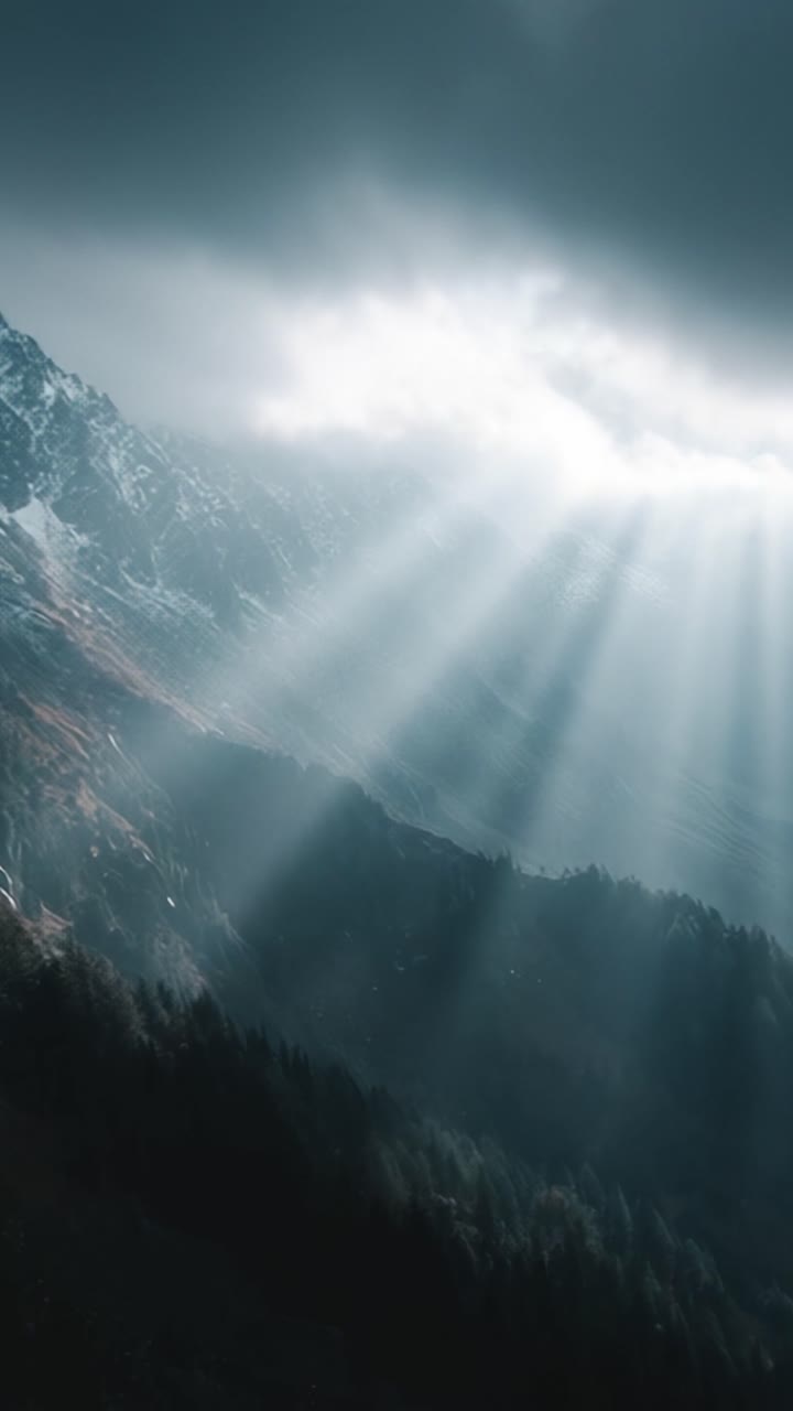 Paesaggio montano drammatico con raggi di luce che filtrano tra le nuvole, mostrando cime maestose e foreste verdi lussureggianti sotto cieli che si oscurano