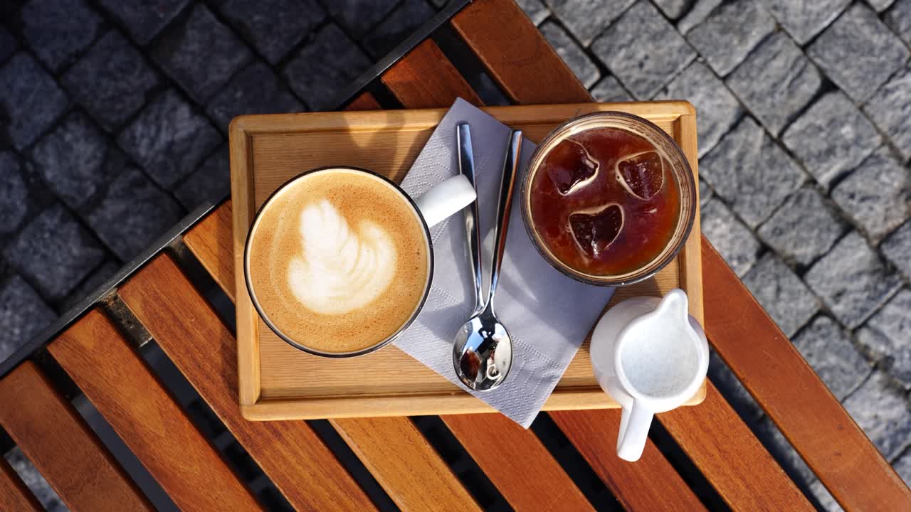 vista de arriba hacia abajo de café helado y tazas de latte con cucharas en la mesa al aire libre de madera