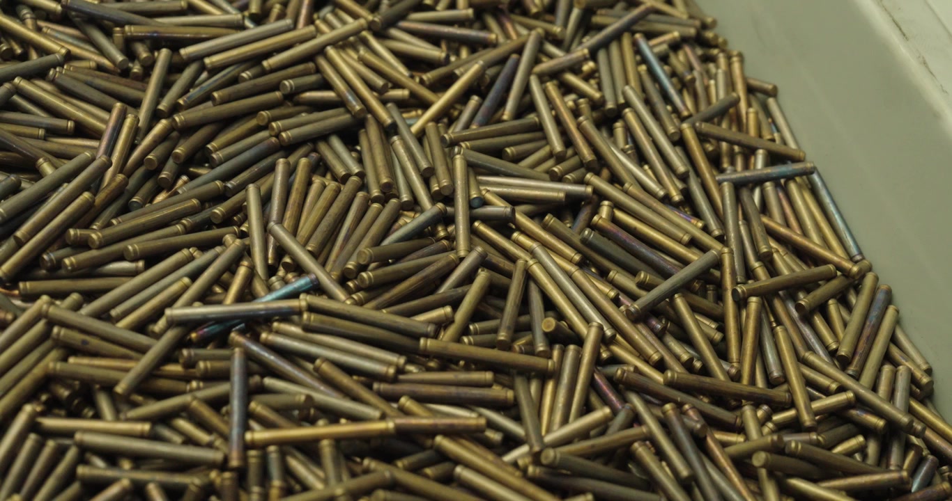 Close-up of hardened precision metal pins in a container, used for industrial manufacturing, engineering, machining, and mechanical assembly.
