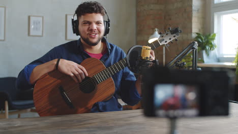 músico masculino filmando un vlog de guitarra con una cámara en un estudio de grabación