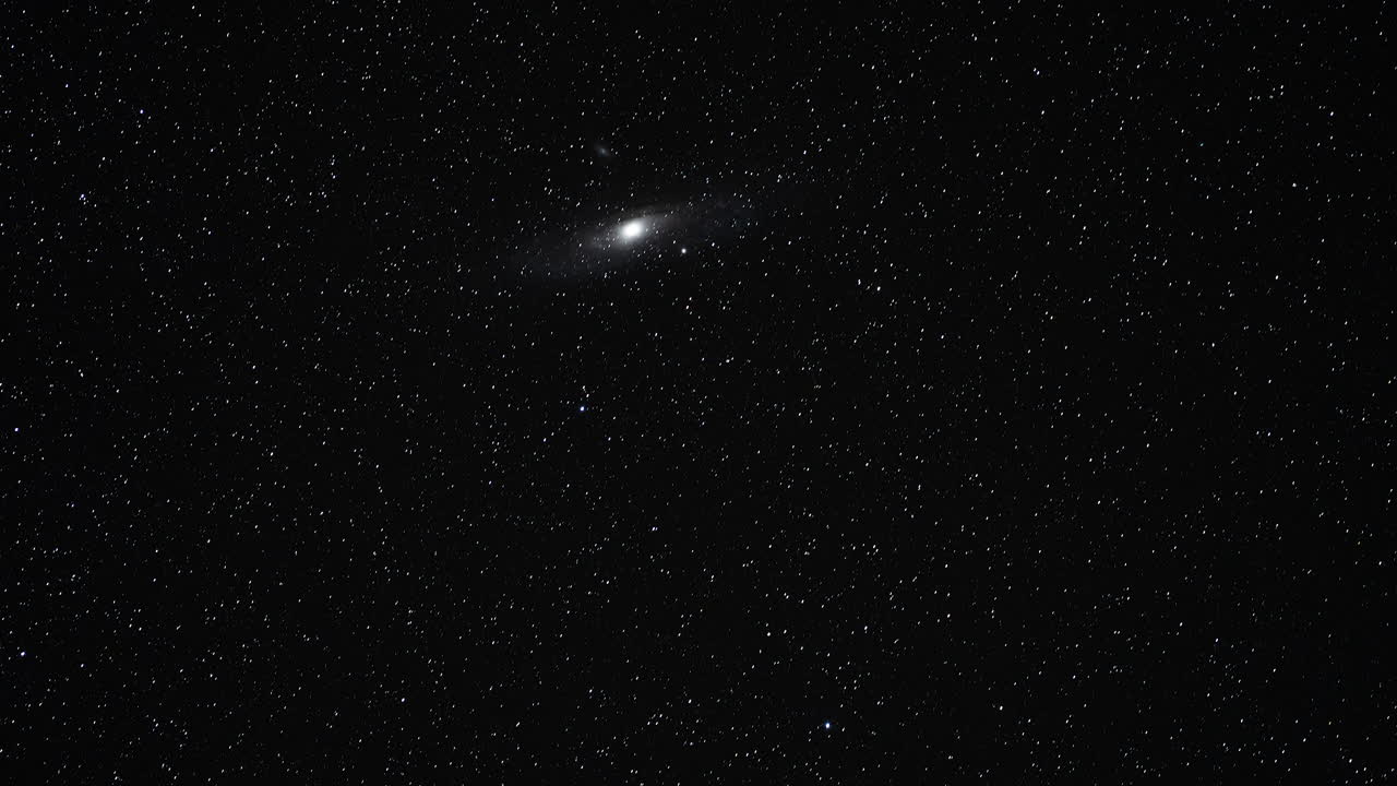Andromeda Galaxy and Stars Drift Across Dark Night Sky