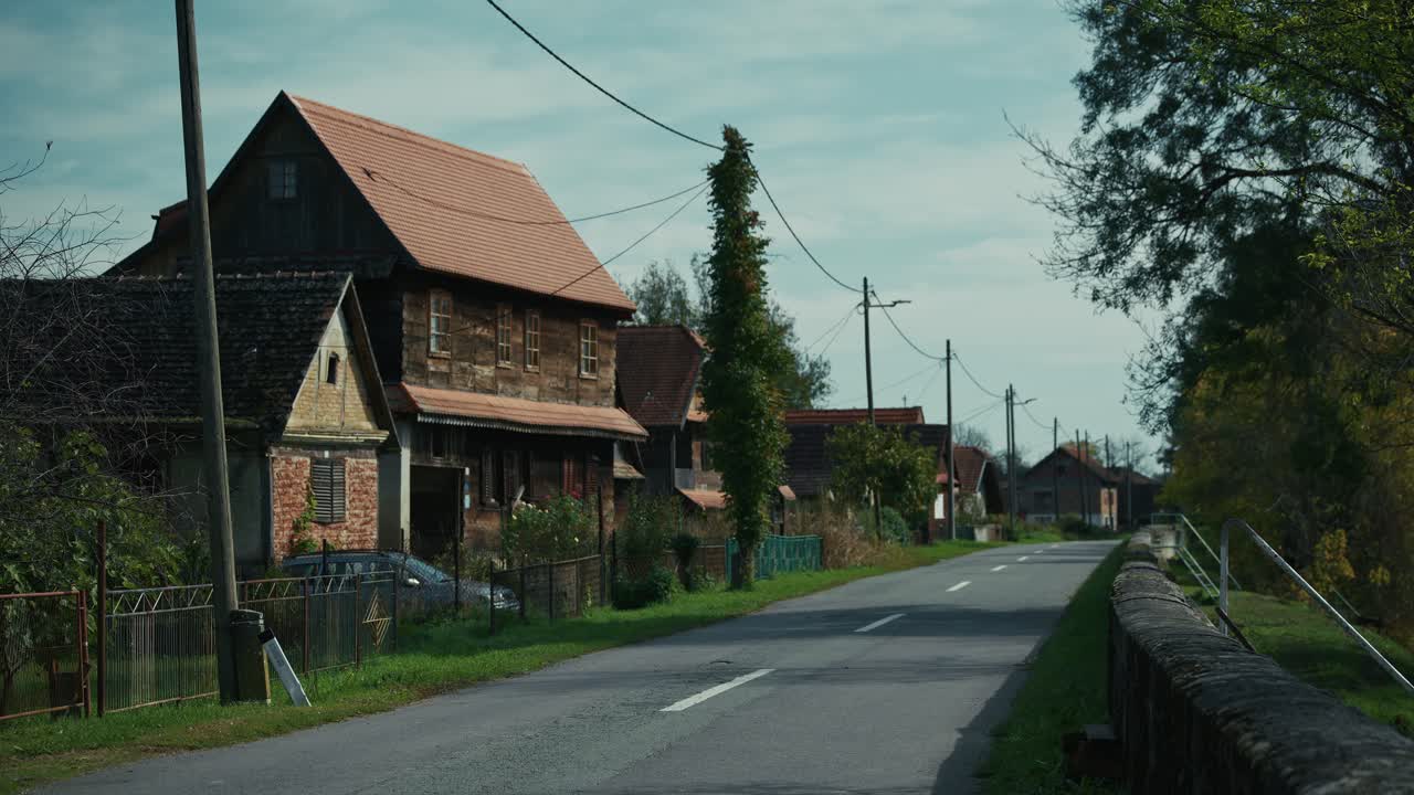 Quiet rural road lined with traditional wooden houses in Lonjsko Polje Krapje Croatia
