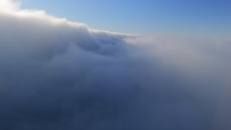 flying through fluffy foggy clouds in the blue sky at daytime