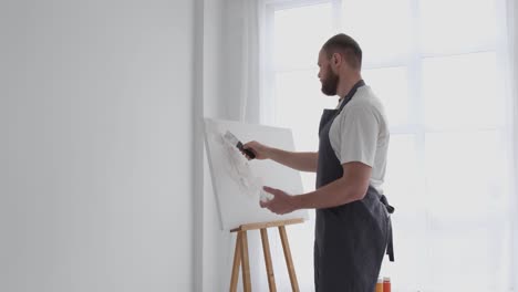 male artist paints a picture with oil paints artist while working in the studio