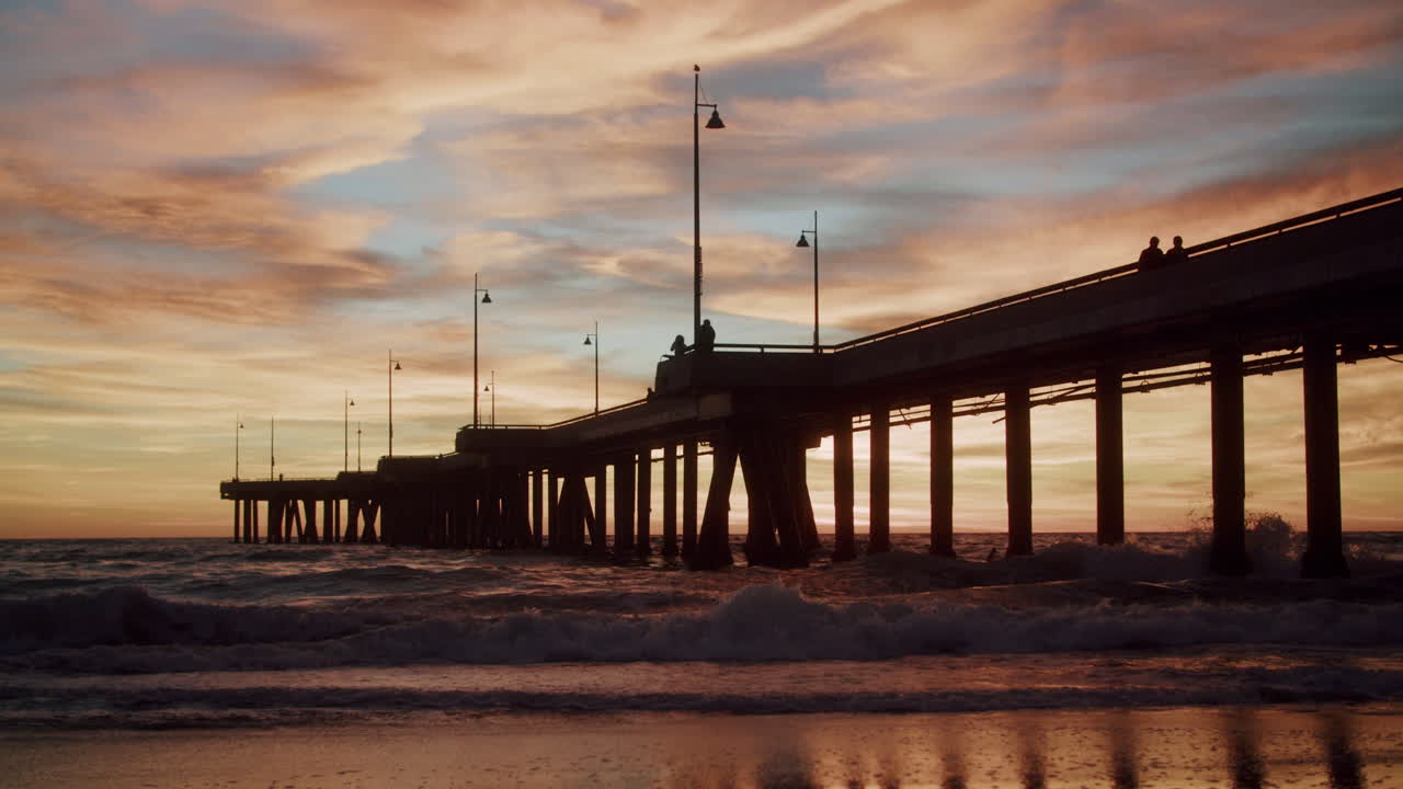 Sunset over the ocean with a pier silhouette