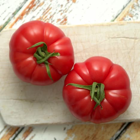 Top-view-of-a-white-cutting-board-with-a-fresh-juicy-tomatoes-on-a-wooden-table