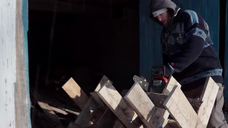 the man is utilizing his chainsaw to cut wood that's positioned on a sawbuck - close up