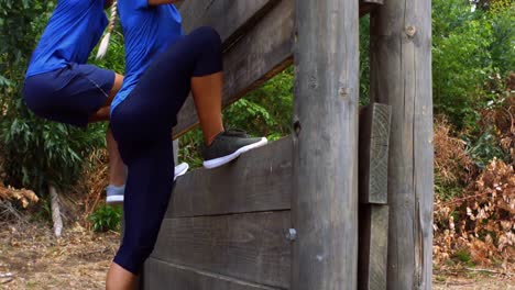 couple climbing a wooden wall during obstacle course