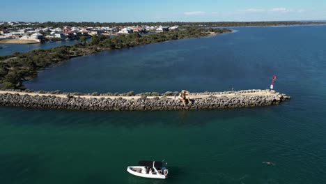 Aerial-pull-out-of-peninsula-to-reveal-people-diving-off-boat-into-water