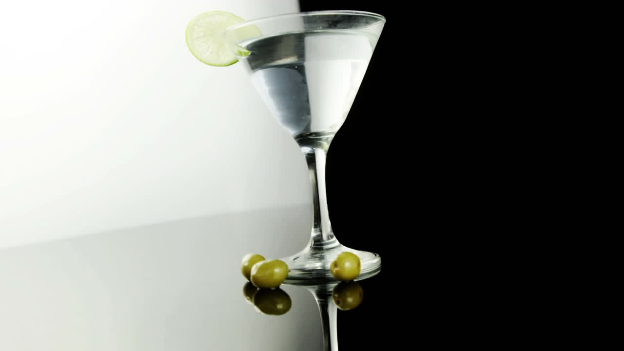 Motivo a chevron su bicchiere da cocktail con spicchio di lime, su sfondo nero.