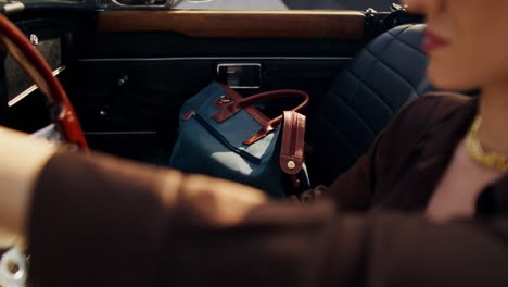 woman driving a vintage convertible with a stylish bag