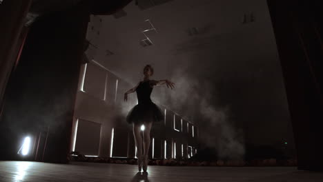 una bailarina bailando lentamente frente a las luces de los reflectores. varios reflectores muestran a una balerina bailando en un escenario oscuro en cámara lenta