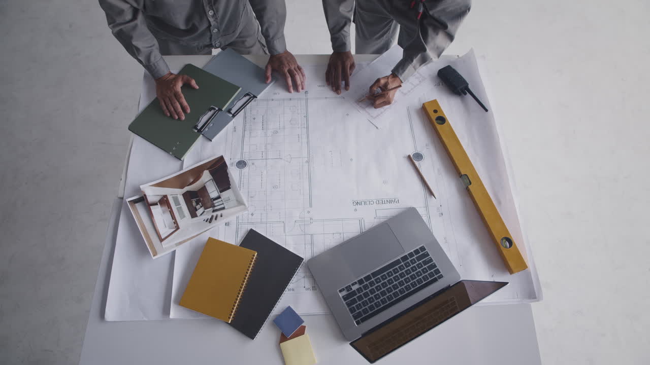 Unrecognizable Engineers Examining Building Blueprint