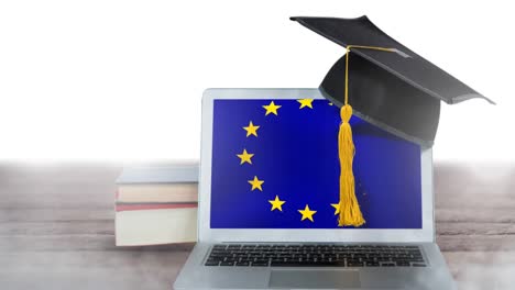 European-flag-waving-on-the-screen-of-a-laptop,-with-books-hat-and-a-wooden-table