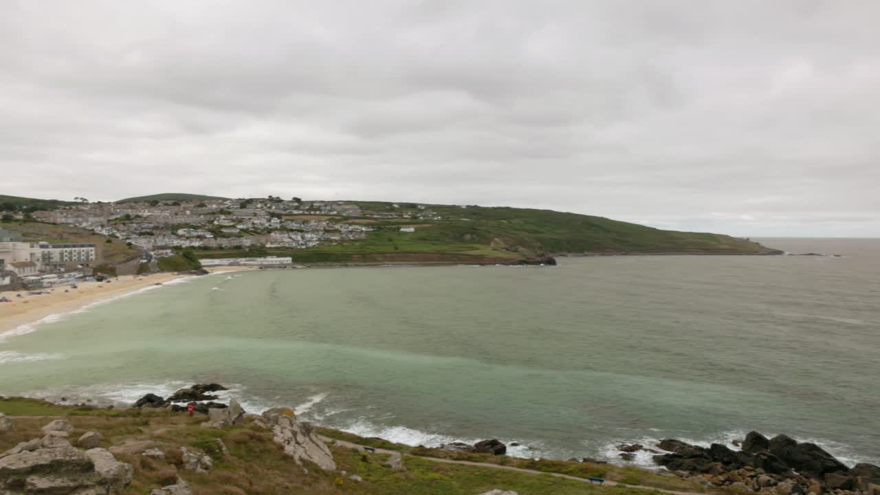Panning shot of Porthmeor Beach with turquoise waters and golden sand in St Ives
