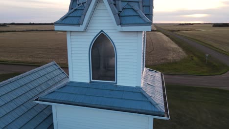 the bell of a wooden christian church behind the steeple's windows