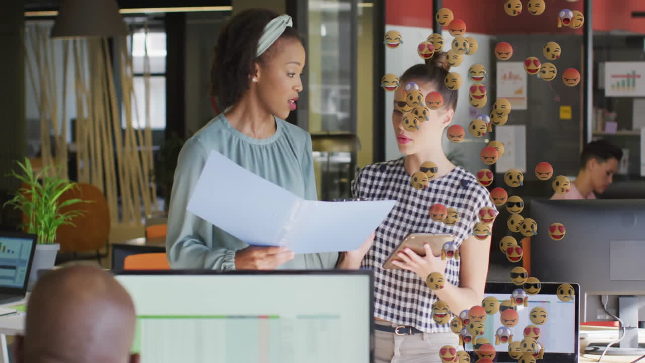 Colleagues reviewing folder and smartphone in business office, showing animated charts and emojis