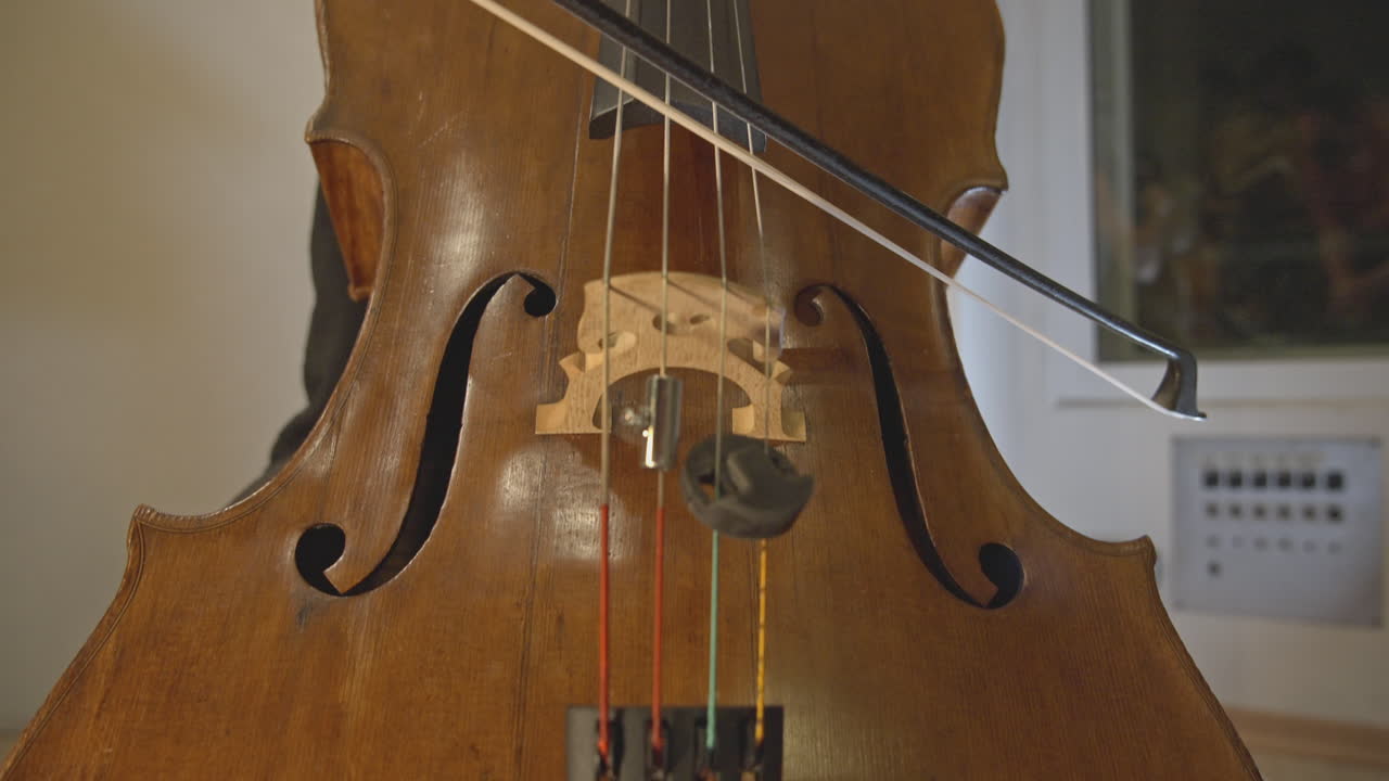 Primo piano di un musicista che suona un violoncello.