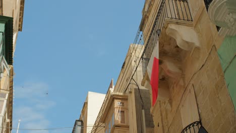 maltese flag hanging on a historic balcony in the three cities