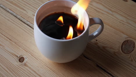 flames rising from coffee in a white mug
