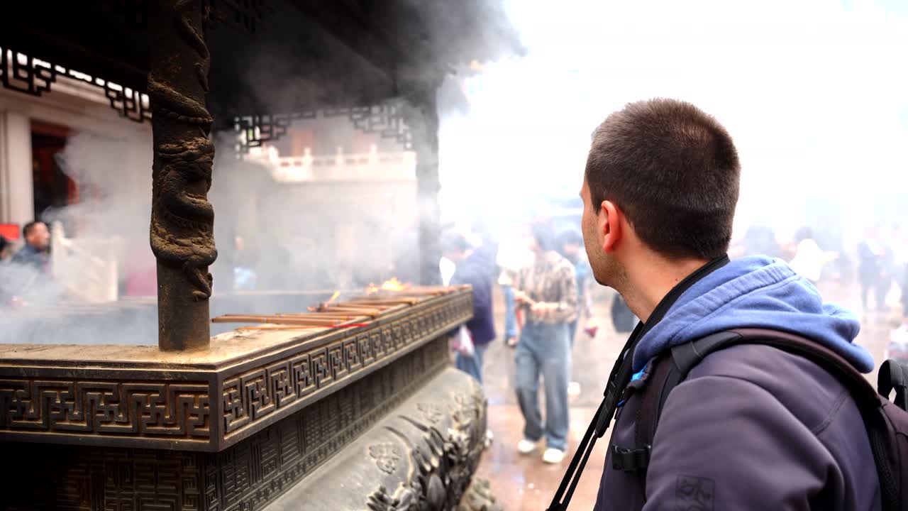 상하이의 진간 사원을 방문하는 남자, 향연 연기에 둘러싸여, 지역 문화를 경험합니다.