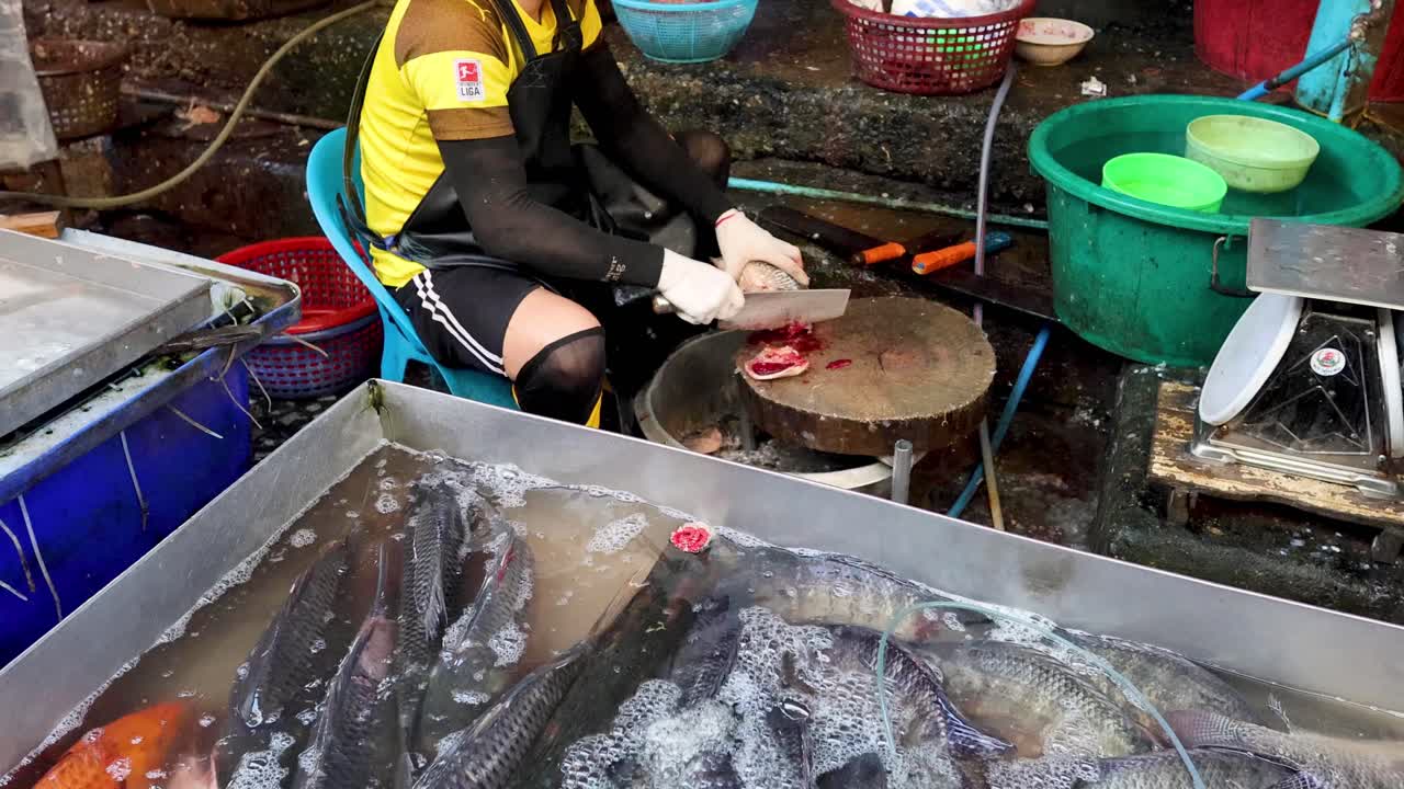 trabajador limpiando peces en un puesto de mercado húmedo