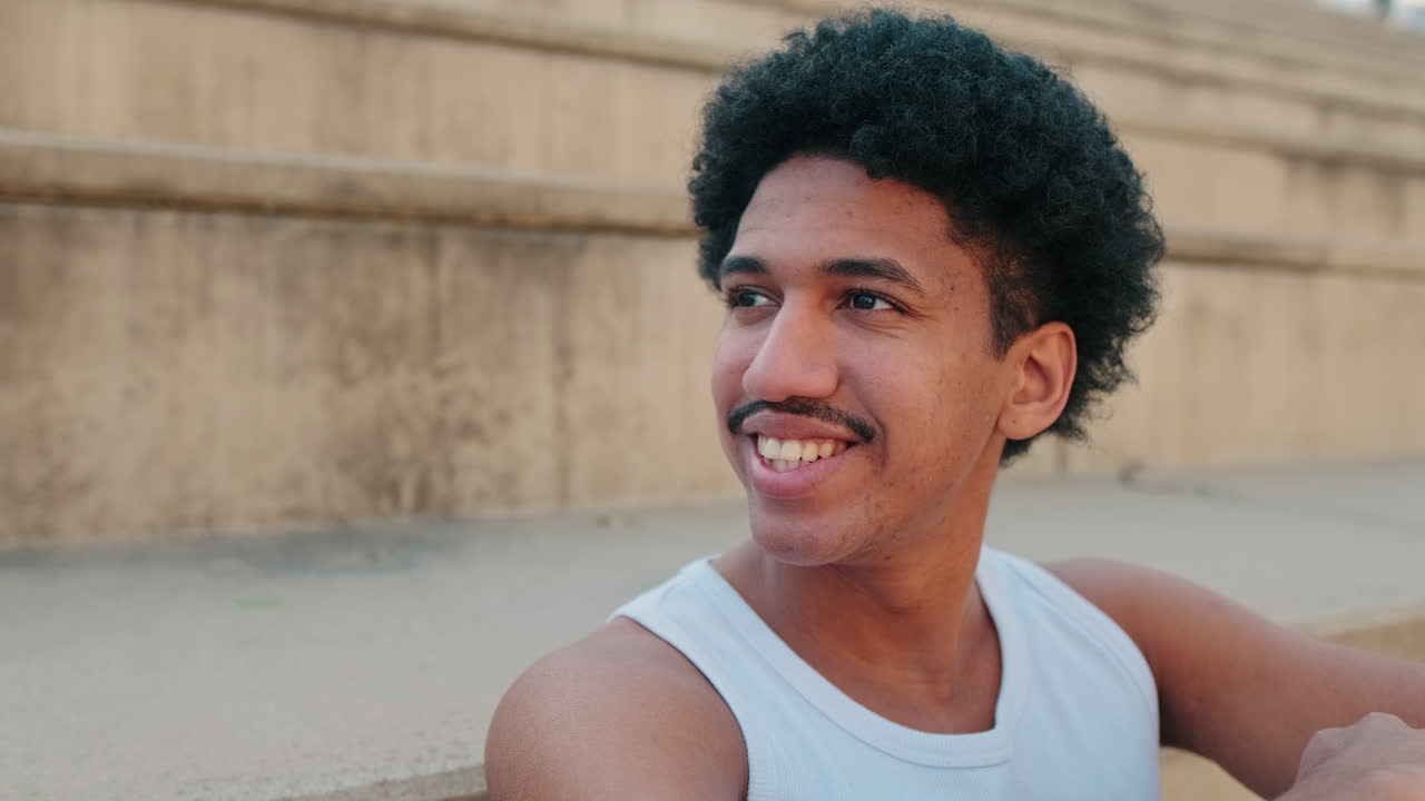 Young Man with Curly Hair Smiling and Then Becoming Thoughtful