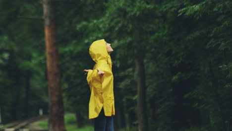 Attraktives-Mädchen-In-Einem-Gelben-Regenmantel,-Der-Ihre-Hände-Hochhebt