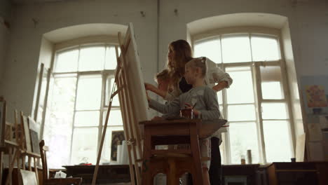 children and teacher painting on easel