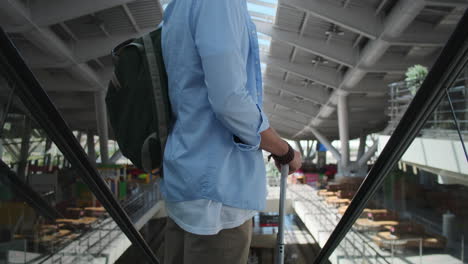 man with luggage on an escalator in a modern shopping mall