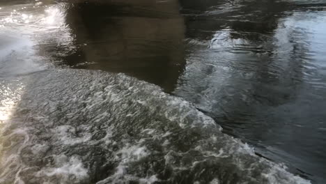 Peaceful-stream-of-water-flowing-under-a-bridge-on-a-sunny-day